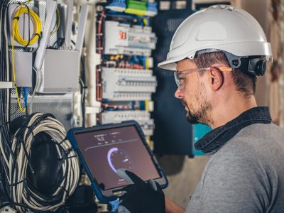 Man, an electrical technician working in a switchboard with fuses. Installation and connection of electrical equipment.